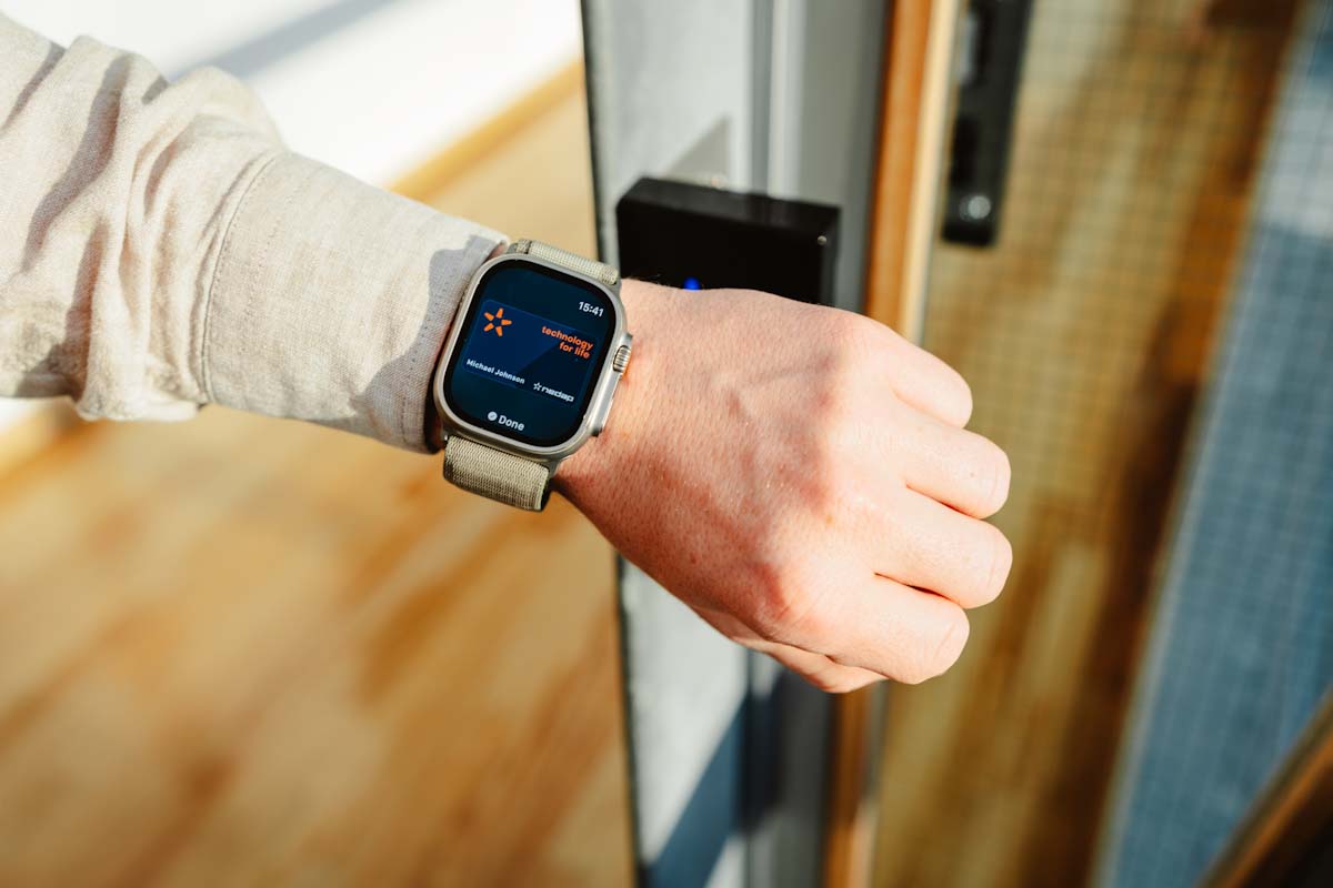 Man die arm met smartwatch bij kaartlezer houdt om toegang tot ruimte te krijgen.